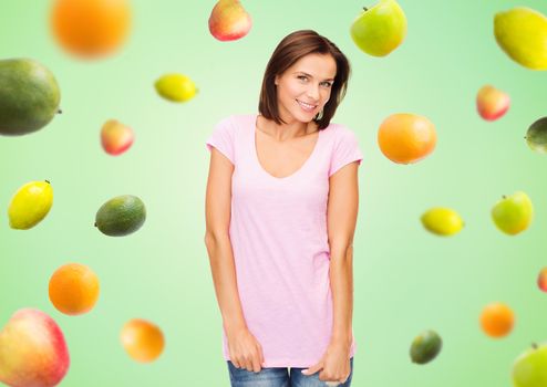 people, advertisement, diet, food and healthy eating concept - happy woman in blank pink t-shirt over fruits on green background