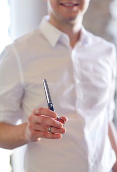 beauty, hairstyle and people concept -close up of male stylist with scissors at salon