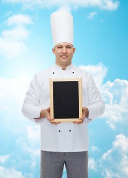 cooking, profession, advertisement and people concept - happy male chef cook showing and holding blank menu board over blue sky with clouds background