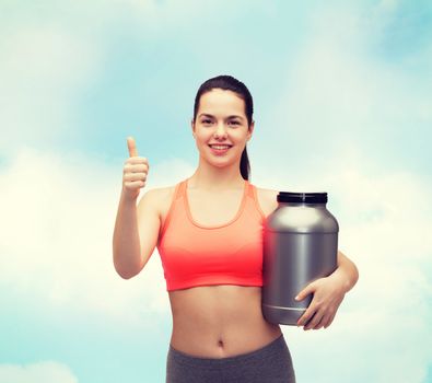 fitness and diet concept - smiling teenage girl with jar of protein showing thumbs up