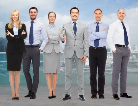 business, people, gesture and office concept - group of smiling businessmen making handshake over city background