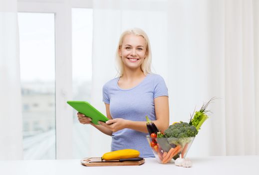 healthy eating, cooking, vegetarian food, technology and people concept - smiling young woman with tablet pc computer and bowl of vegetables at home