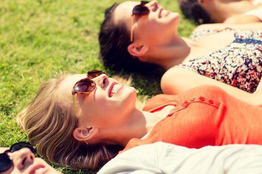 friendship, leisure, summer and people concept - group of smiling friends lying on grass outdoors