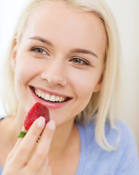 healthy eating, food, fruits, diet and people concept - happy woman eating strawberry at home