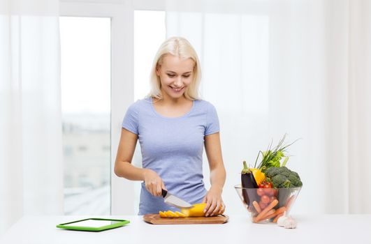 healthy eating, vegetarian food, dieting and people concept - smiling young woman cooking vegetables with tablet pc computer at home