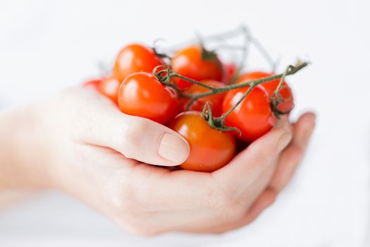 healthy eating, dieting, vegetarian food and people concept - close up of woman hands holding cherry tomatoes bunch at home