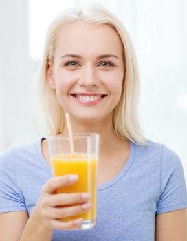 healthy eating, vegetarian food, diet, detox and people concept - smiling woman drinking orange juice or shake from glass at home