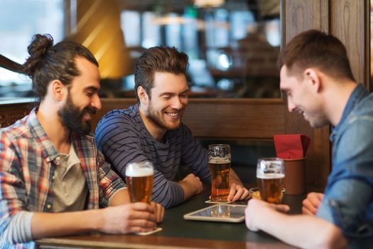 people, men, leisure, friendship and technology concept - happy male friends with tablet pc computer drinking beer at bar or pub