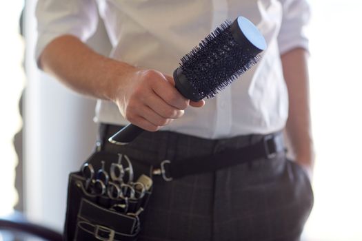 beauty, hairstyle and people concept - close up of male stylist with brush at salon