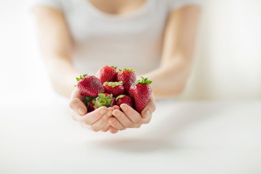 healthy eating, dieting, vegetarian food and people concept - close up of woman hands holding strawberries at home