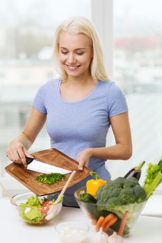 healthy eating, vegetarian food, dieting and people concept - smiling young woman cooking vegetable salad at home