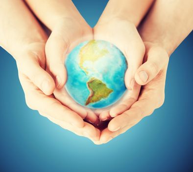 people, geography, population and peace concept - close up of woman and man hands with earth globe showing american continent over blue background