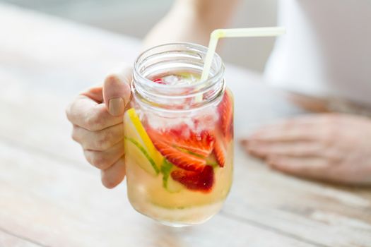 healthy eating, drinks, diet, detox and people concept - close up of happy woman holding glass with fruit water at home