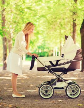 family, child and parenthood concept - happy mother with stroller in park