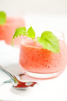 Smoothie drink with mint leafs on table, in high key