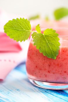 Smoothie drink with mint leafs on table, in high key