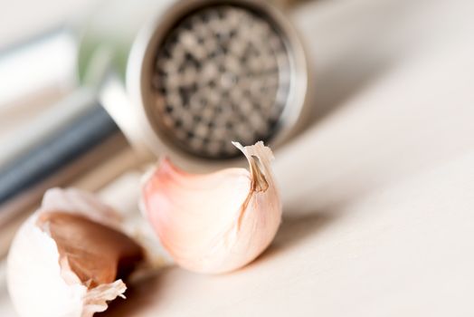 Garlic and garlic press on wooden table