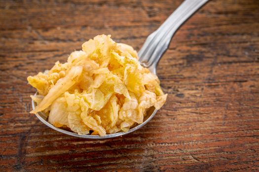 tablespoon of traditional Korean kimchi (fermented napa cabbage with garlic and onion) against rustic wood table