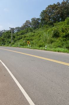 The road on the mountains. The road cuts through the mountains. The trees along the road