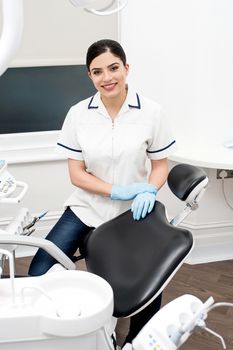 Female dental assistant sitting beside dental chair