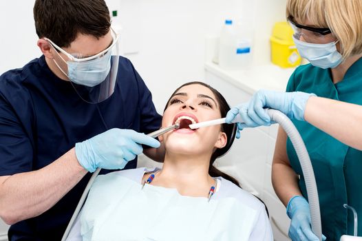 Dentist treating patient teeth with assistant