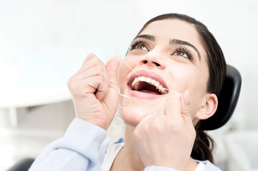 Woman using dental floss for cleaning her teeth