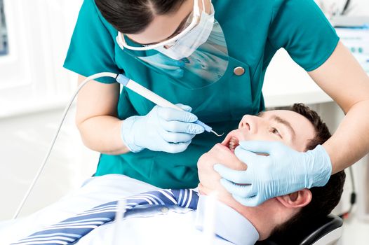 Male with open mouth during oral checkup at dentist