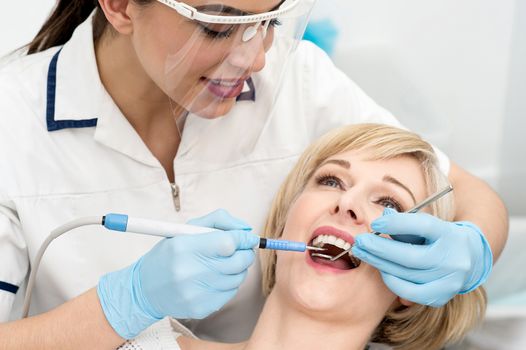 Female dentist procedure of teeth cleaning