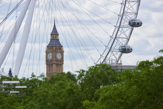 LONDON, UK - JUNE 15: Big Ben framed by London Eye cables, with two of the structure's capsules in the frame. June 15, 2015 in London. Both London Eye and Big Ben are famous landmarks in London.