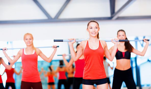 fitness, sport, training, gym and lifestyle concept - group of smiling people working out with barbells in the gym