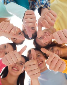 friendship, youth, gesture and people - group of smiling teenagers in a circle showing thumbs up