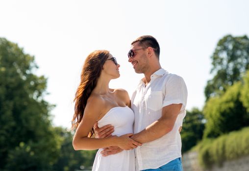 love, travel, tourism, people and friendship concept - smiling couple wearing sunglasses hugging in city