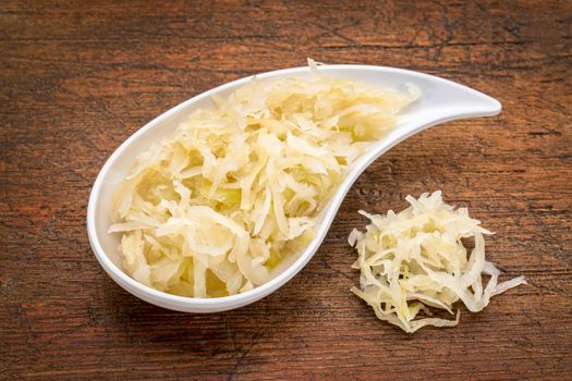 teardrop shaped bowl of sauerkraut against rustic wood - healthy eating concept