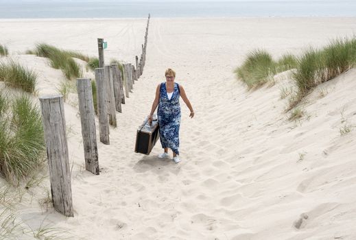 woman with suitcase walking from the beach