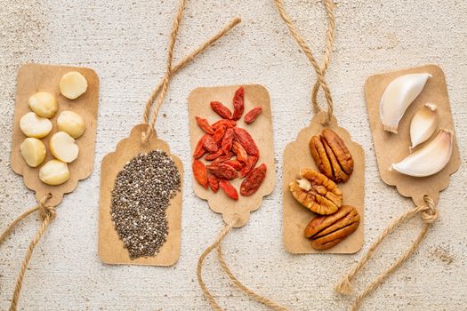 superfood abstract with price tags against  rustic barn wood (macadamia and pecan nuts, goji berries, chia seeds and garlic cloves) - healthy eating concept