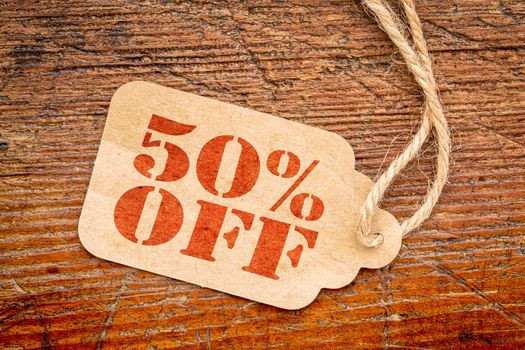 fifty percent off - a paper price tag against rustic wood - sale concept