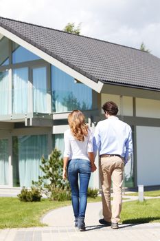 couple walking towards house while holding hands