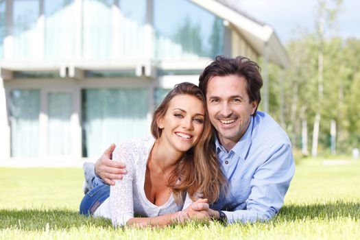 happy couple lying in front of their house