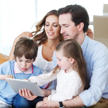 happy family looks at tablet while sitting on the couch