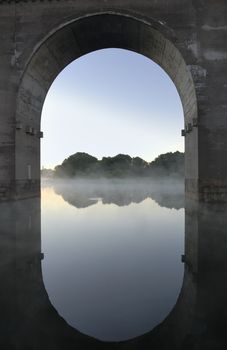 An old bridge in Stockholm Sweden made of concrete. The vault mirroring in the water.