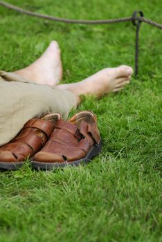 Hiker resting on grass. Shoes off, bare feet.