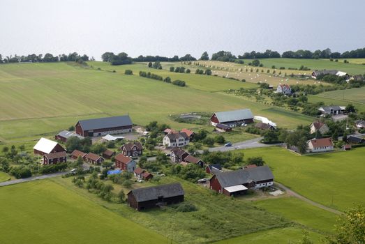 A view over cornfields in summertime with farms and lake  "Vatterna" (Sweden) in the background.