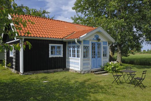 Small brown cottage by a green summer meadow.