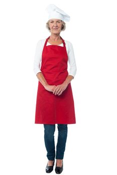 Full length of aged woman chef with hands clasped