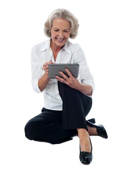 Seated elderly woman operating digital tablet