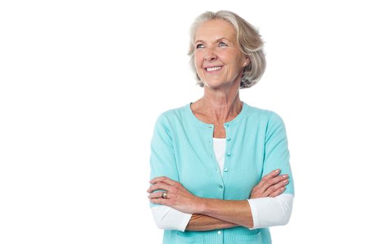 Senior smiling woman looking up with arms crossed