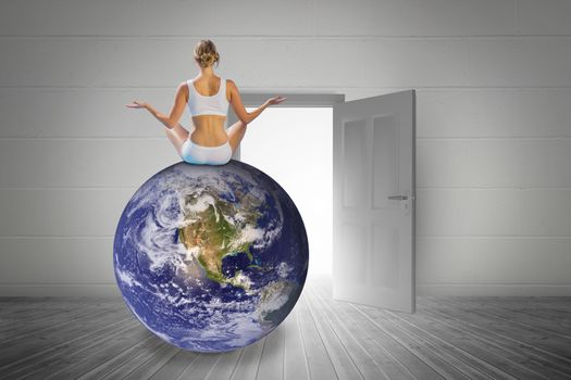 Fit woman doing yoga against open door on white wall