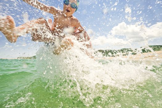 Splashes over an excited kid, thrown in to the see water by his father on a sunny day at the beach.