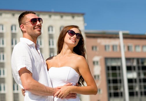 love, travel, tourism, people and friendship concept - smiling couple wearing sunglasses hugging in city