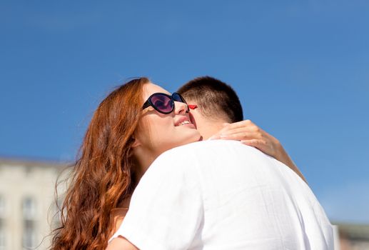 love, wedding, summer, dating and people concept - smiling couple wearing sunglasses hugging in city